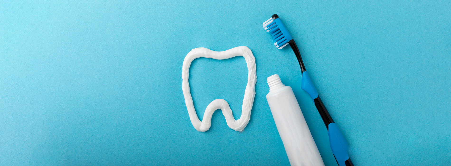 The image shows a toothbrush with toothpaste on a blue surface.