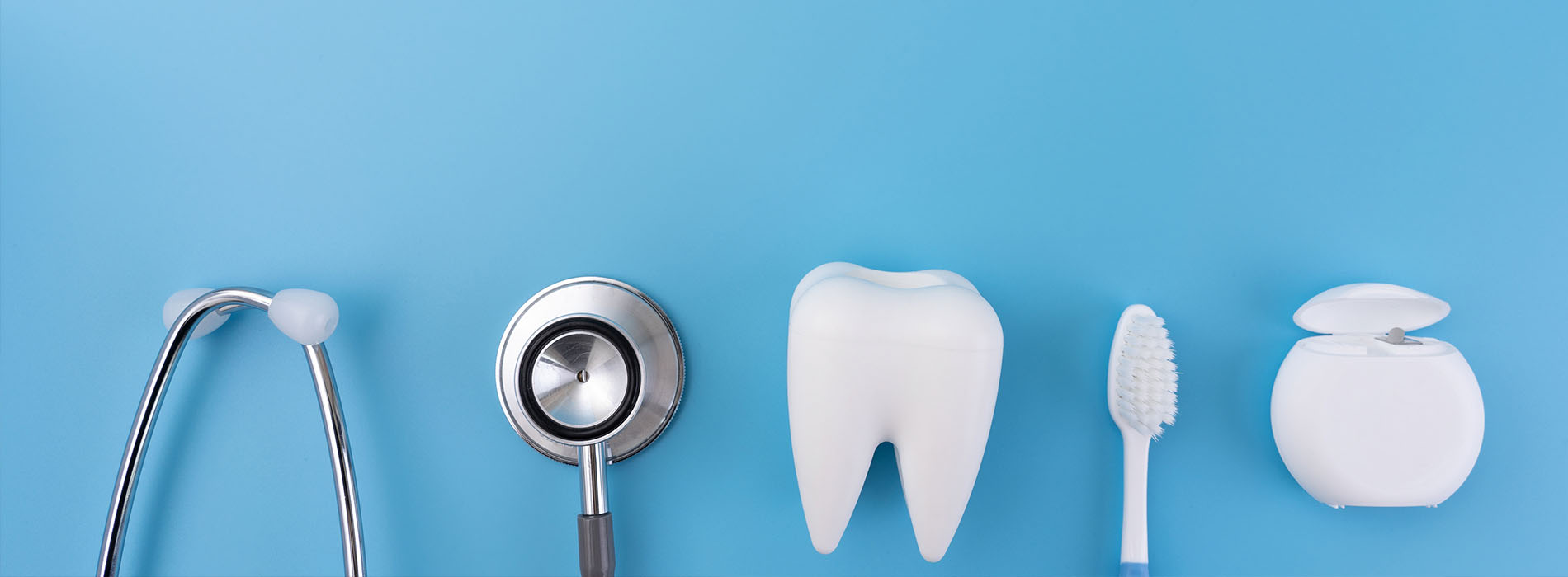 The image displays a collection of dental care items arranged on a blue background, including a toothbrush, toothpaste, floss, mouthwash, and dental tools such as a mirror and a probe, alongside a stethoscope.